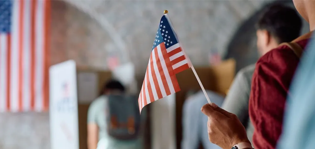 A person holding a flag while standing in line to vote