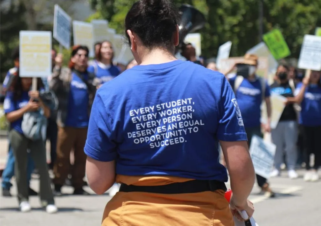 Photo of a demonstrator whose shirt reads "Every Student, Every Worker, Every Person Deserves an Equal Opportunity to Succeed"
